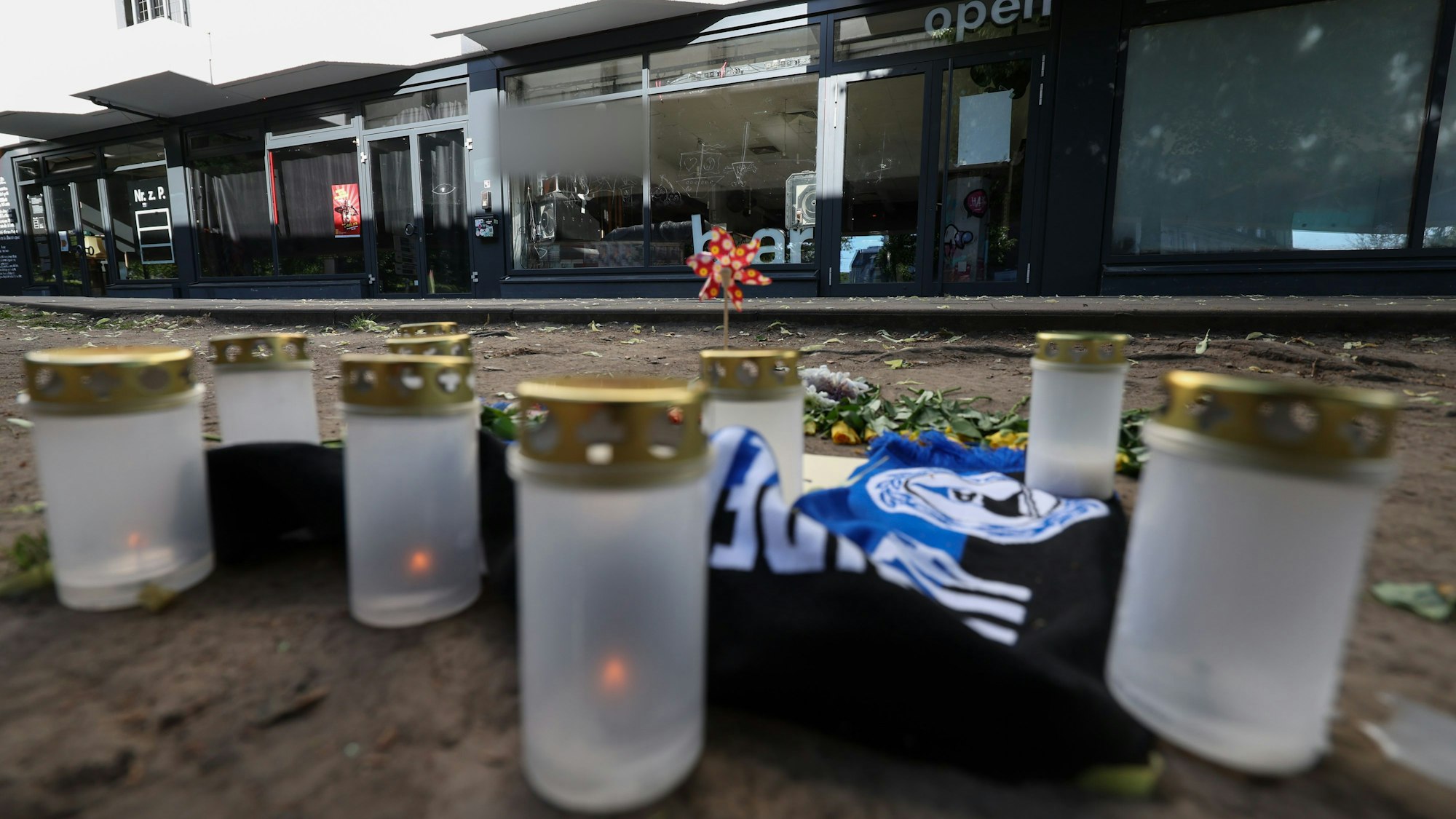 Kerzen und ein Fanschal von Arminia Bielefeld sind an einem Tatort in der Innenstadt zu sehen.