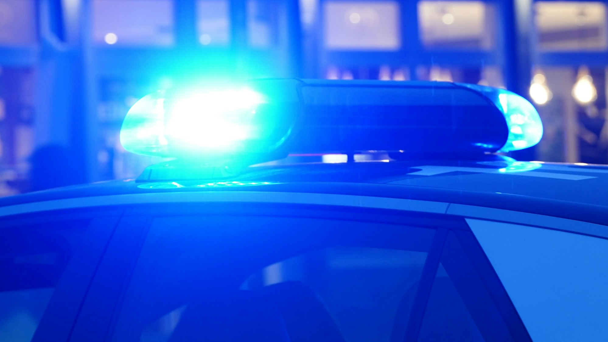 Ein Streifenwagen der Polizei steht mit eingeschaltetem Blaulicht an einem Einsatzort.
