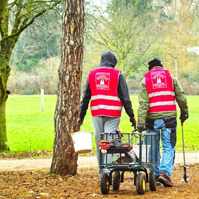 Drei Männer im Volksgarten sammeln Müll