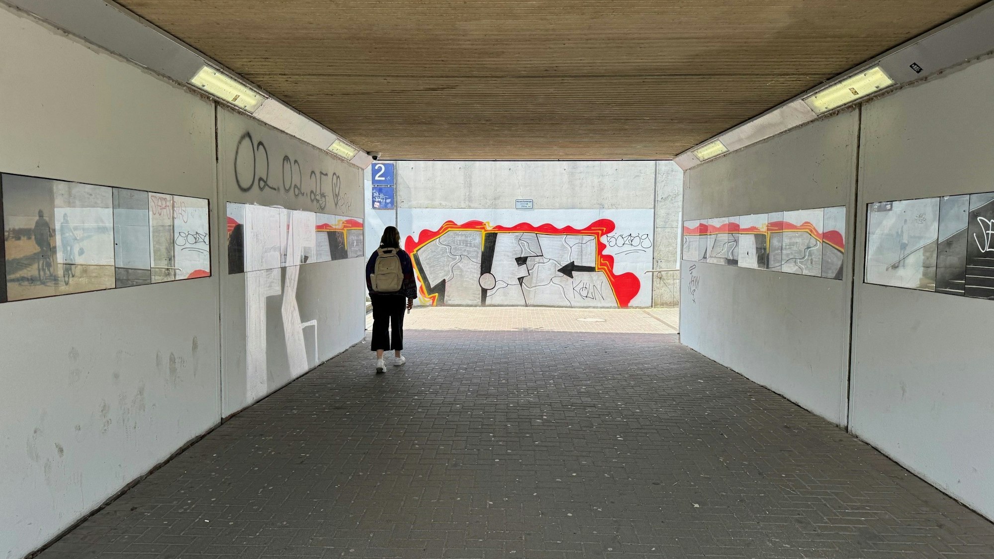 Ein Unterführung, an den Wänden rechts und links sind Fotos zu erkennen.