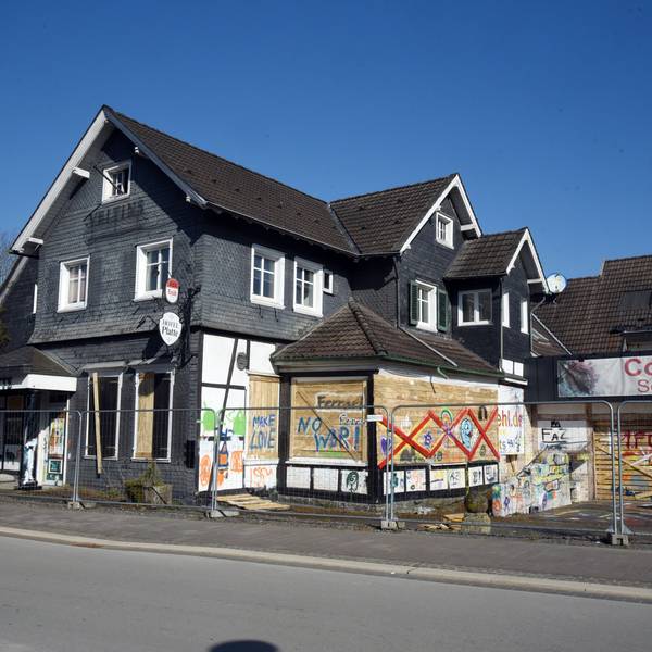 Ein altes Haus mit verbretterten Fenstern und besprühter Fassade.