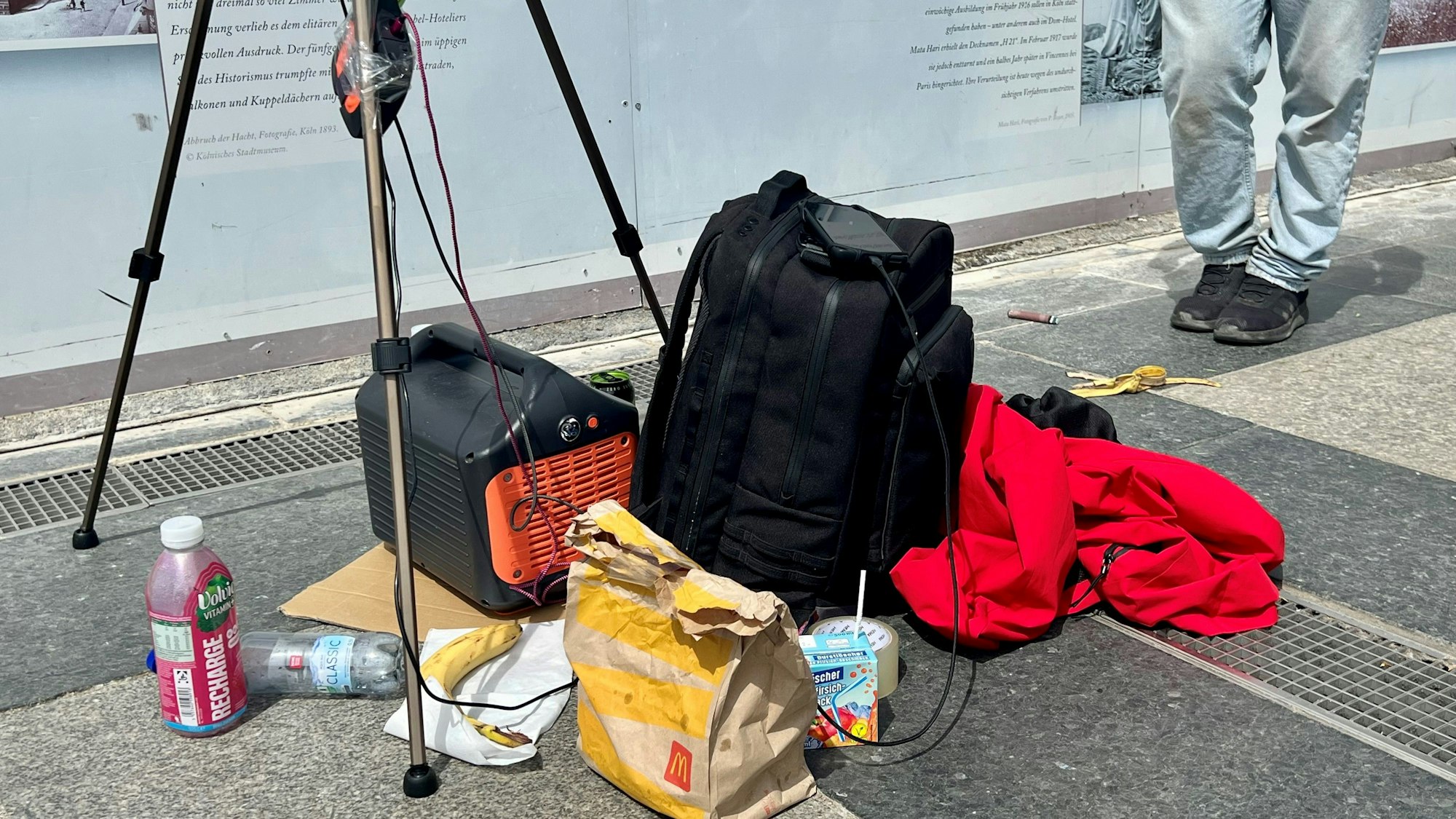 Auf dem Boden stehen unter anderem Getränke und eine Fast-Food-Tüte.