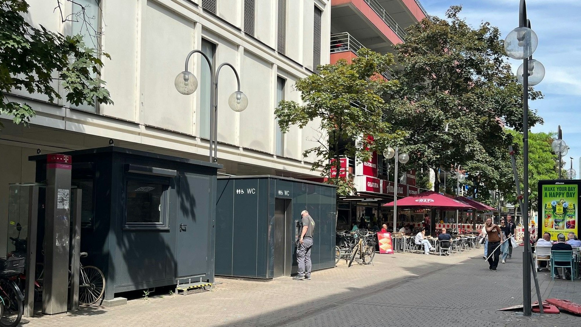 Der Wachmann hat sein Wachhäuschen verlassen und steht vor dem Toilettencontainer.