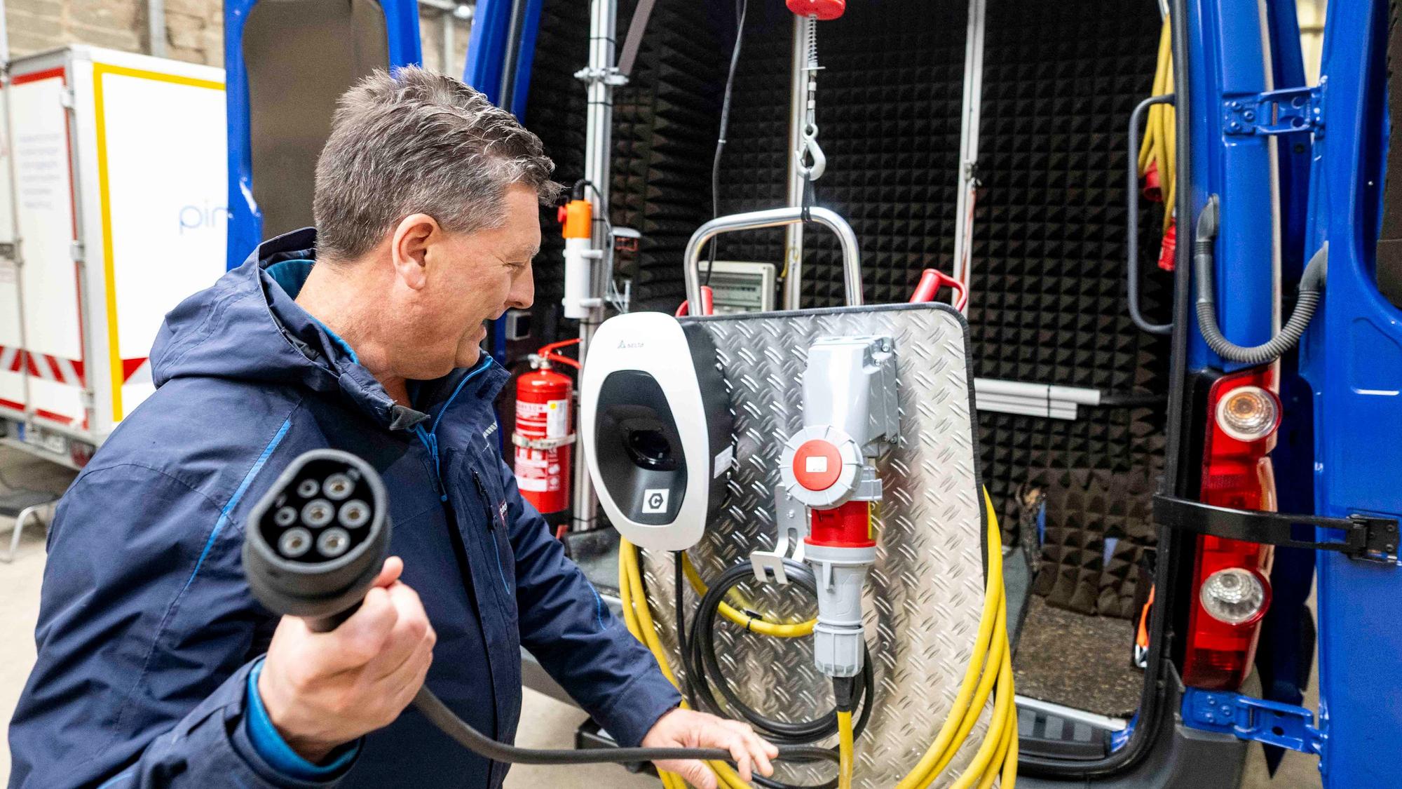 Das Bild zeigt Michael Meierhof, der den Stecker in der rechten Hand hält, mit dem ein E-Auto geladen werden kann.