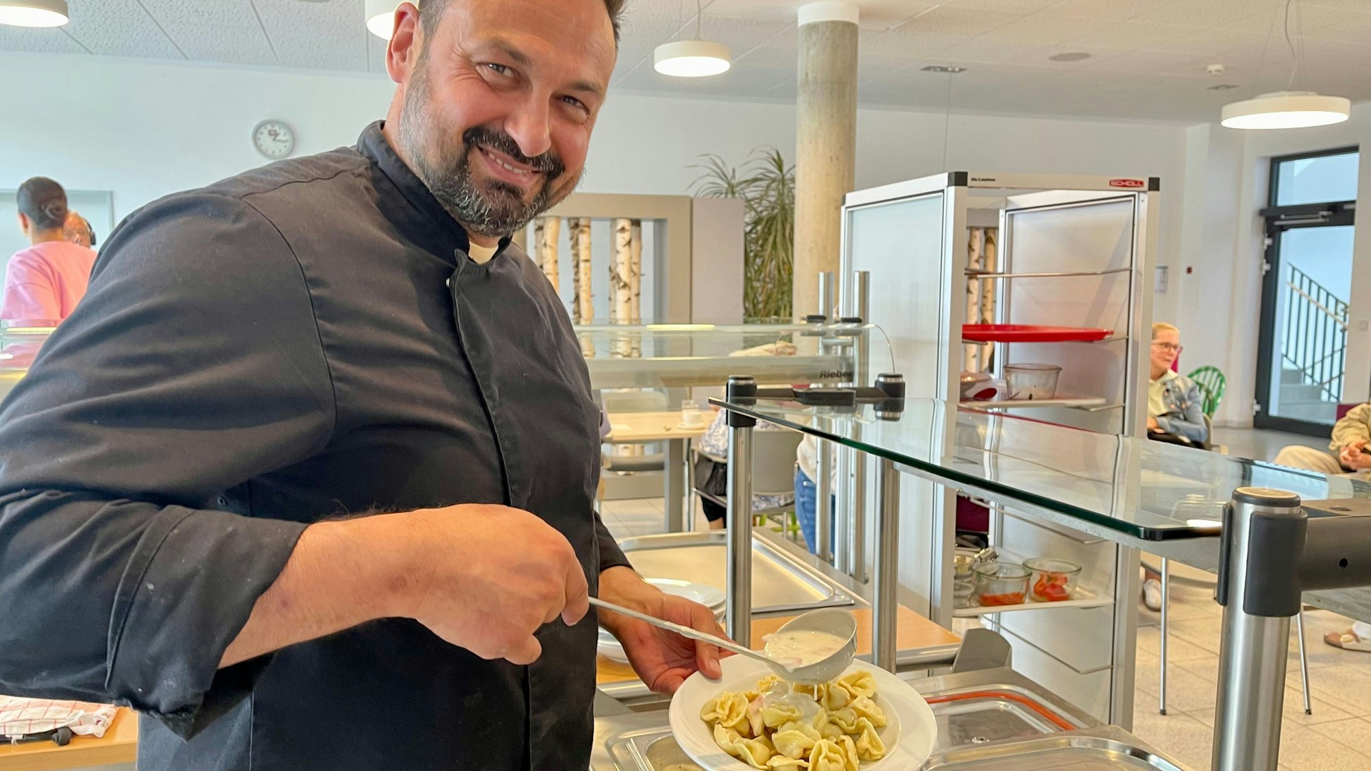 Yannik Steinbach, Leiter des Bistros Pauline in Siegburg, füllt Tortellini auf einen Teller: Der preiswerte Mittagstisch ist auch ein Angebot für Senioren.