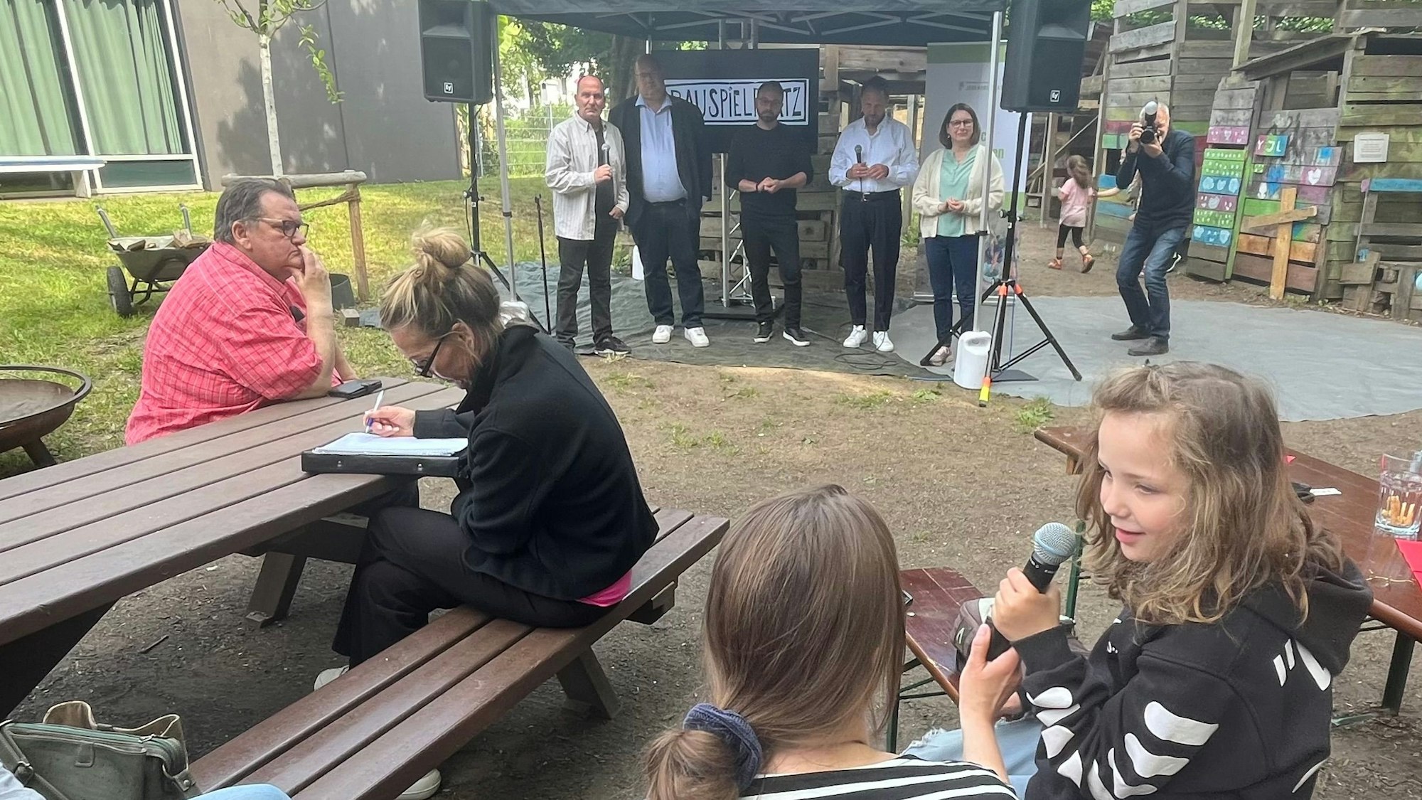 Kind am Mikrofon, Menschen im Hintergrund.