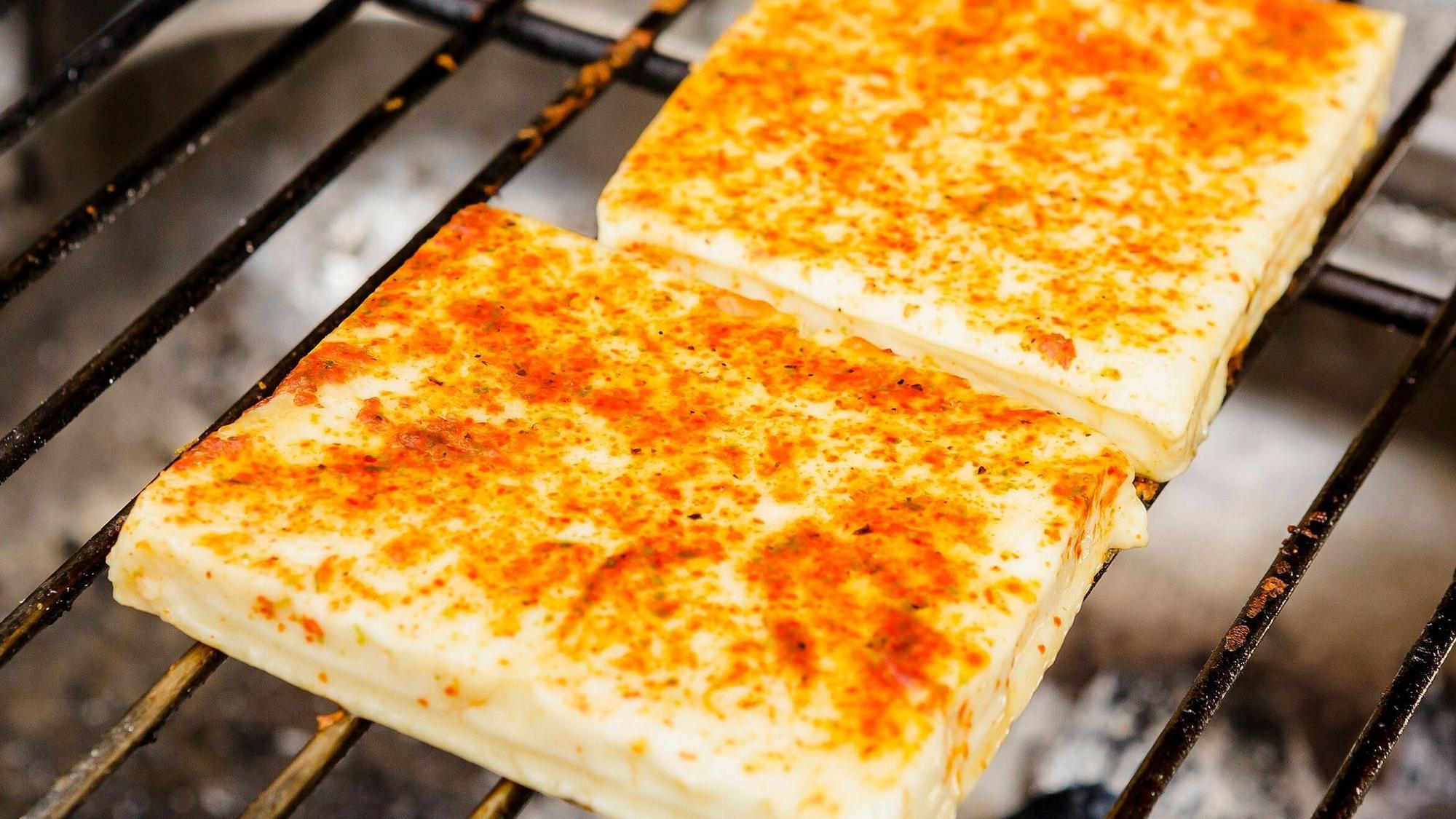 Ein Grillkäse liegt auf dem heißen Rost.