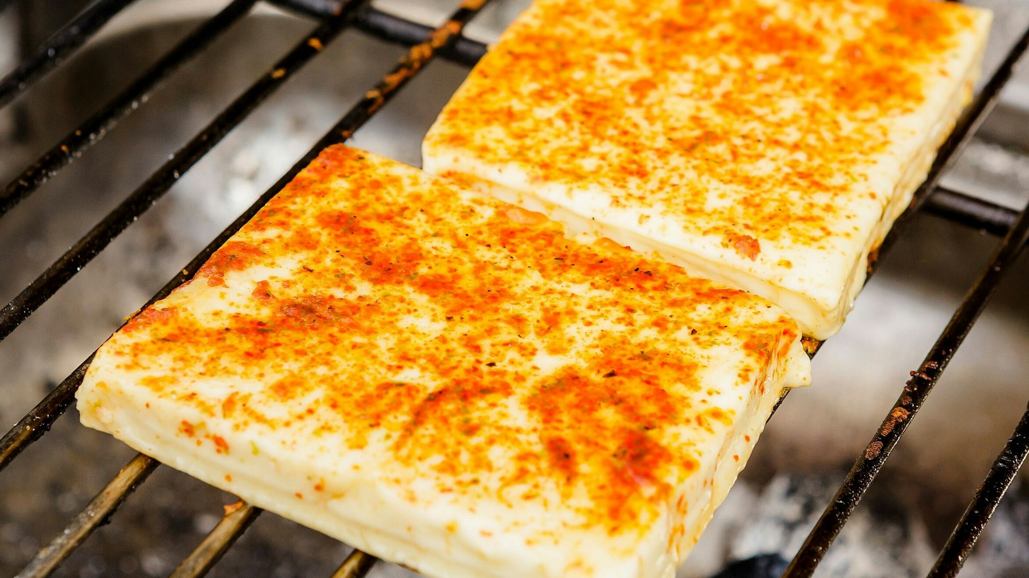 Ein Grillkäse liegt auf dem heißen Rost.