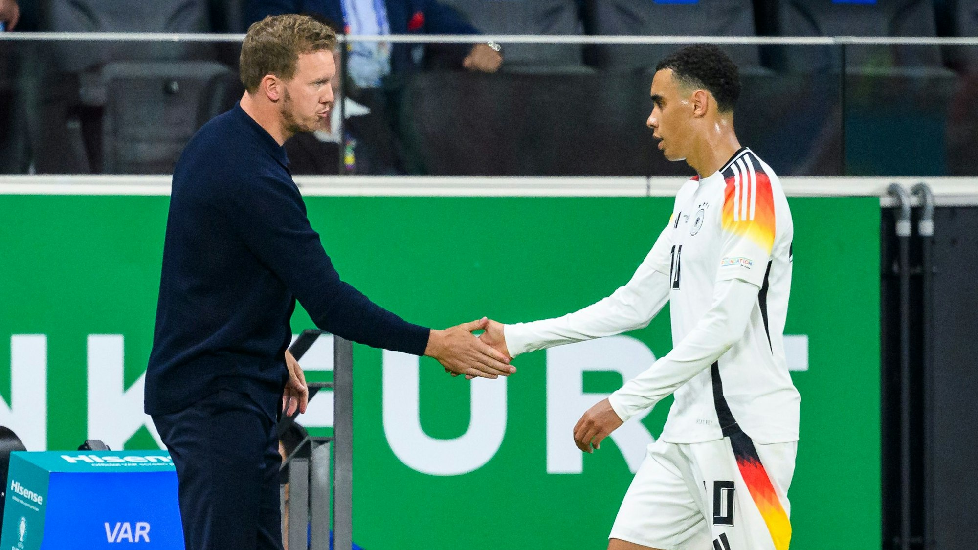 Bundestrainer Julian Nagelsmann (l) klatscht mit Deutschlands Jamal Musiala (r) nach der Auswechslung ab.