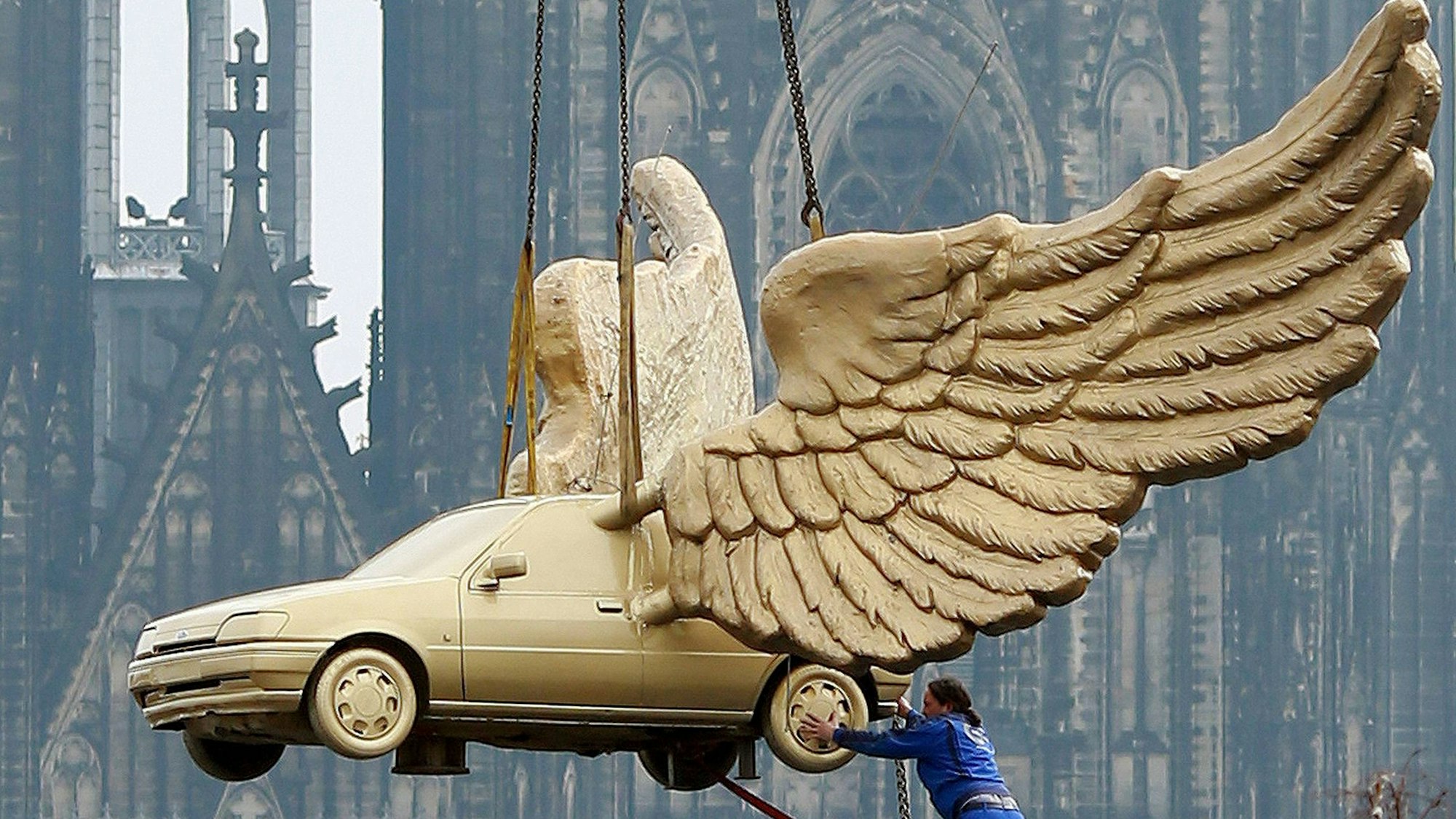 Das Flügelauto des Aktionskünstlers HA Schult hängt an einem Kran und wird auf den Turm des Kölnischen Stadtmuseums in Köln gesetzt.