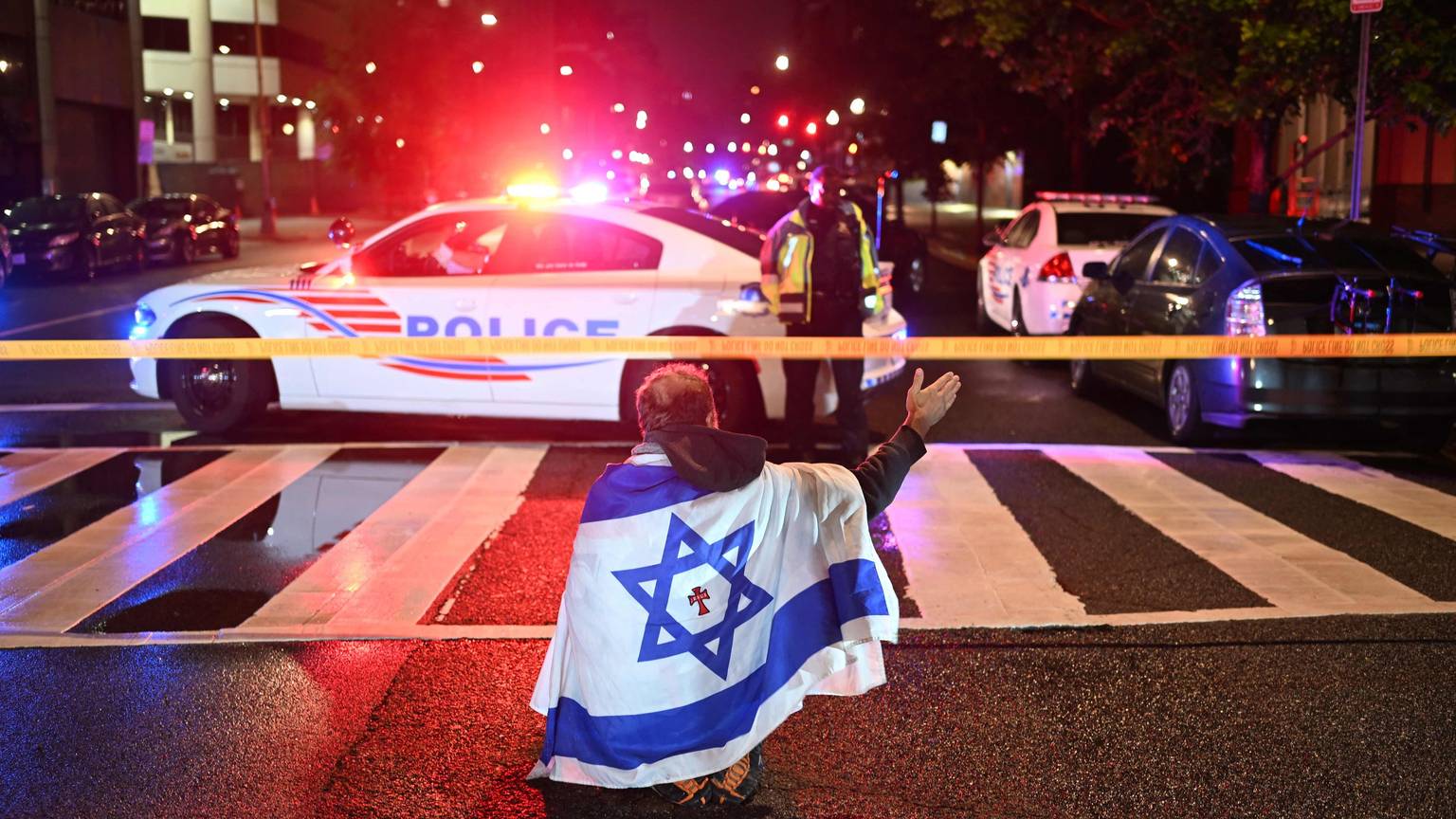 Ein Mann, der die israelische Flagge mit einem Kreuz und dem Namen „Jesus“ in der Mitte trägt, gestikuliert, während Beamte der Metropolitan Police das Gebiet sichern