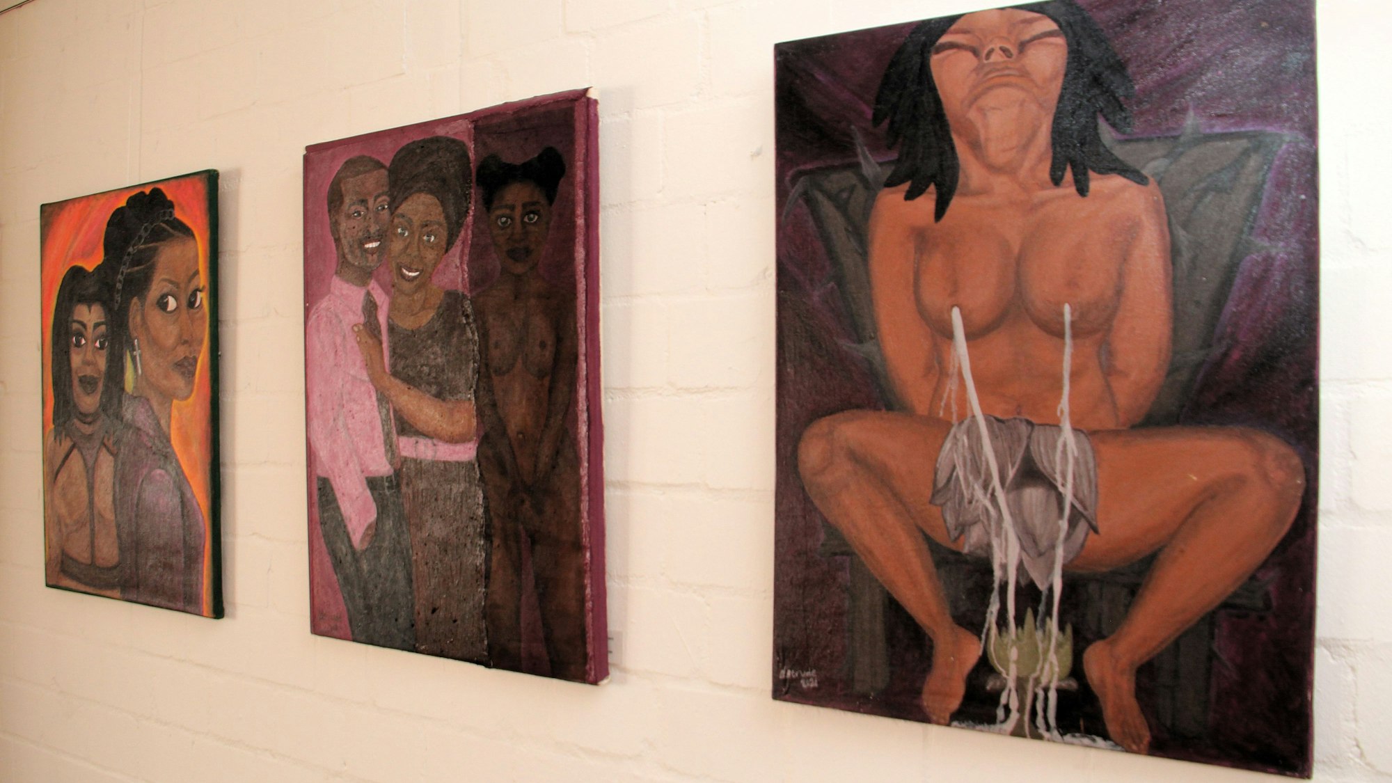 Drei Bilder, die Frauengestalten zeigen, hängen nebeneinander an einer weißen Wand.