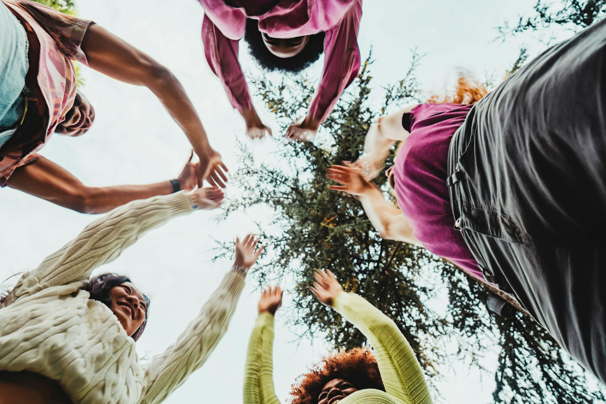 Fünf junge Frauen stehen im Kreis und strecken die Arme in die Höhe.