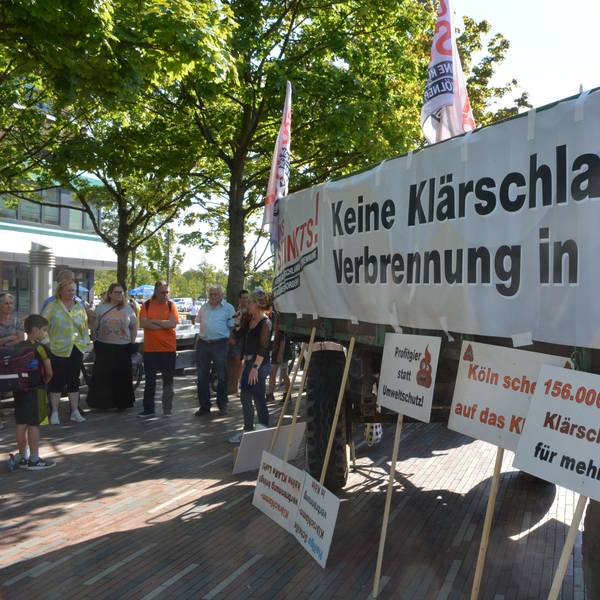 Transparente gegen den Klärschlamm und einige Menschen sind zu sehen.