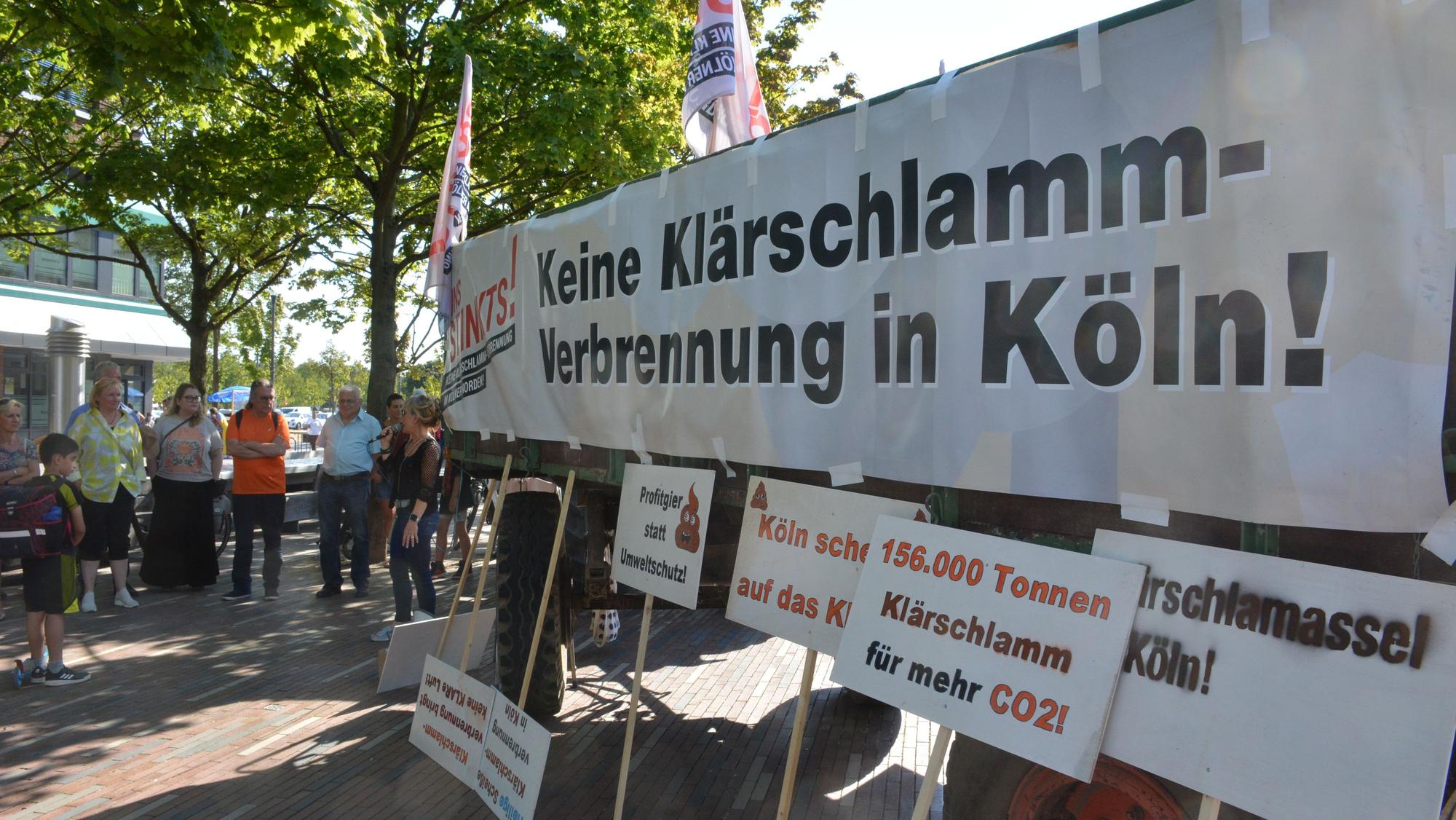 Transparente gegen den Klärschlamm und einige Menschen sind zu sehen.