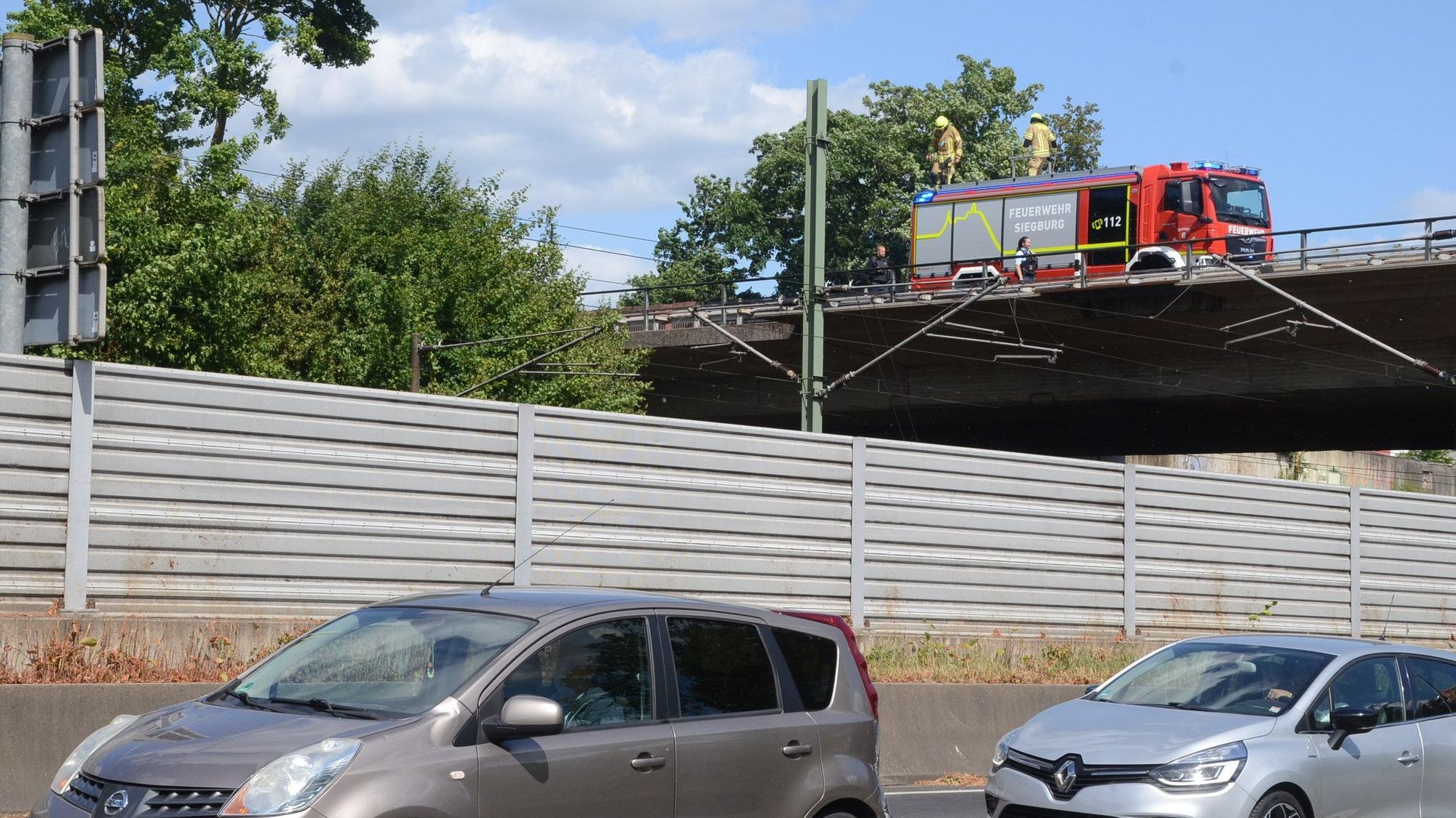 Feuerwehrleute kontrollieren den Bereich an der Bahntrasse von der Umgehungsstraße aus.