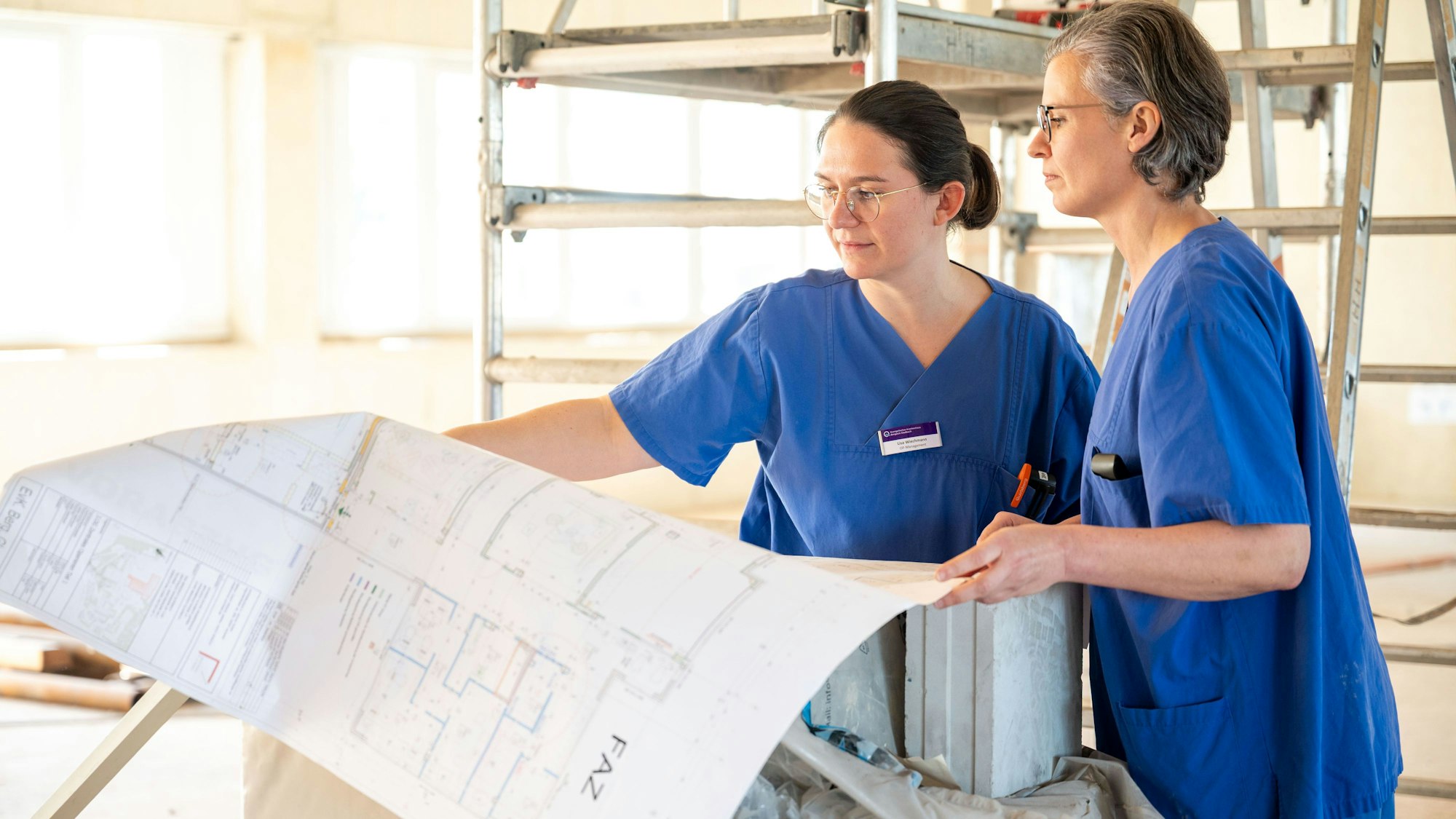 Zwei Mitarbeiterinnen des EVK haben die Baupläne für das geplante OP-Zentrum in den Händen.
