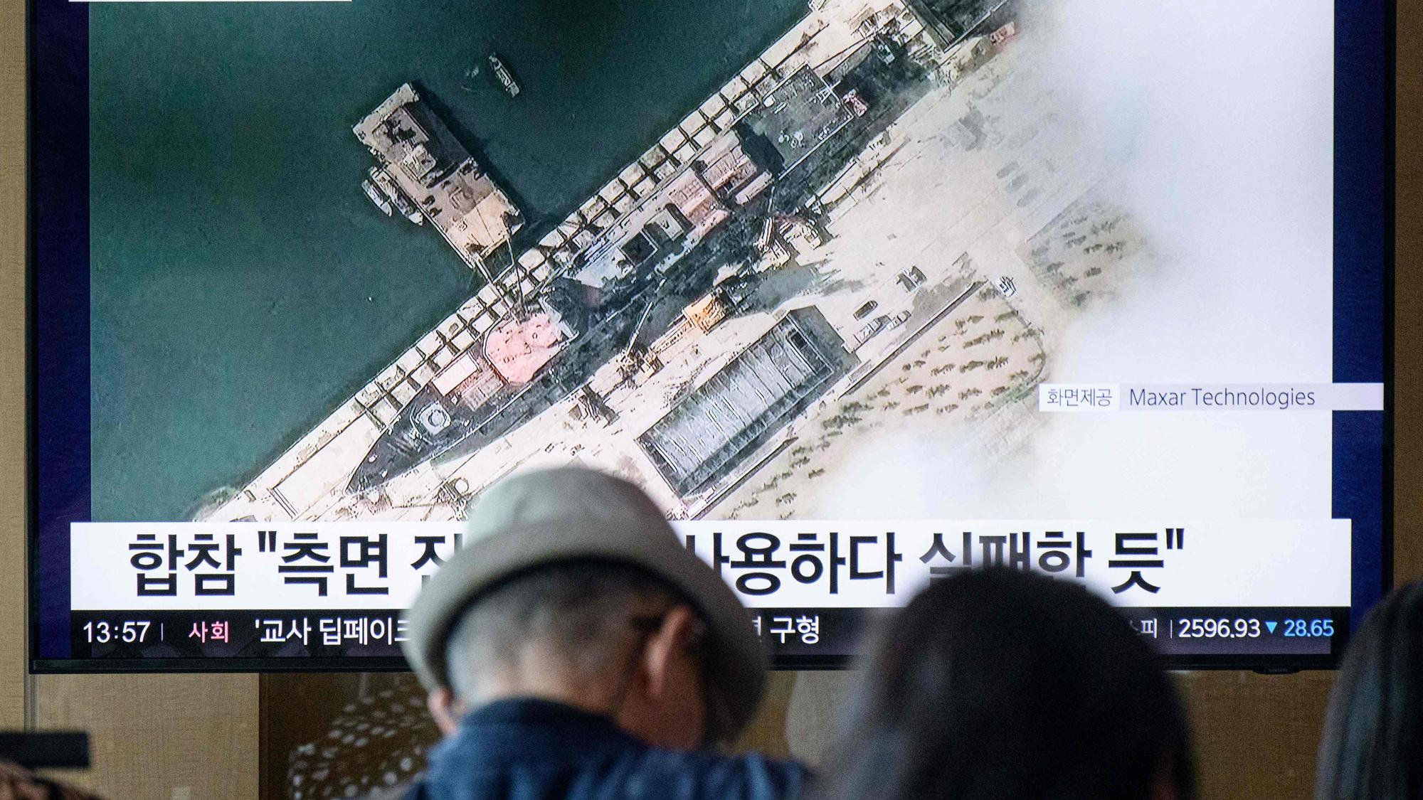 Menschen betrachten ein Satellitenbild, das von Maxar Technologies am 18. Mai 2025 aufgenommen und am 22. Mai 2025 zur Verfügung gestellt wurde und eine Gesamtansicht eines neuen nordkoreanischen Kriegsschiffs im Hafen von Chongjin zeigt. (Archivbild)