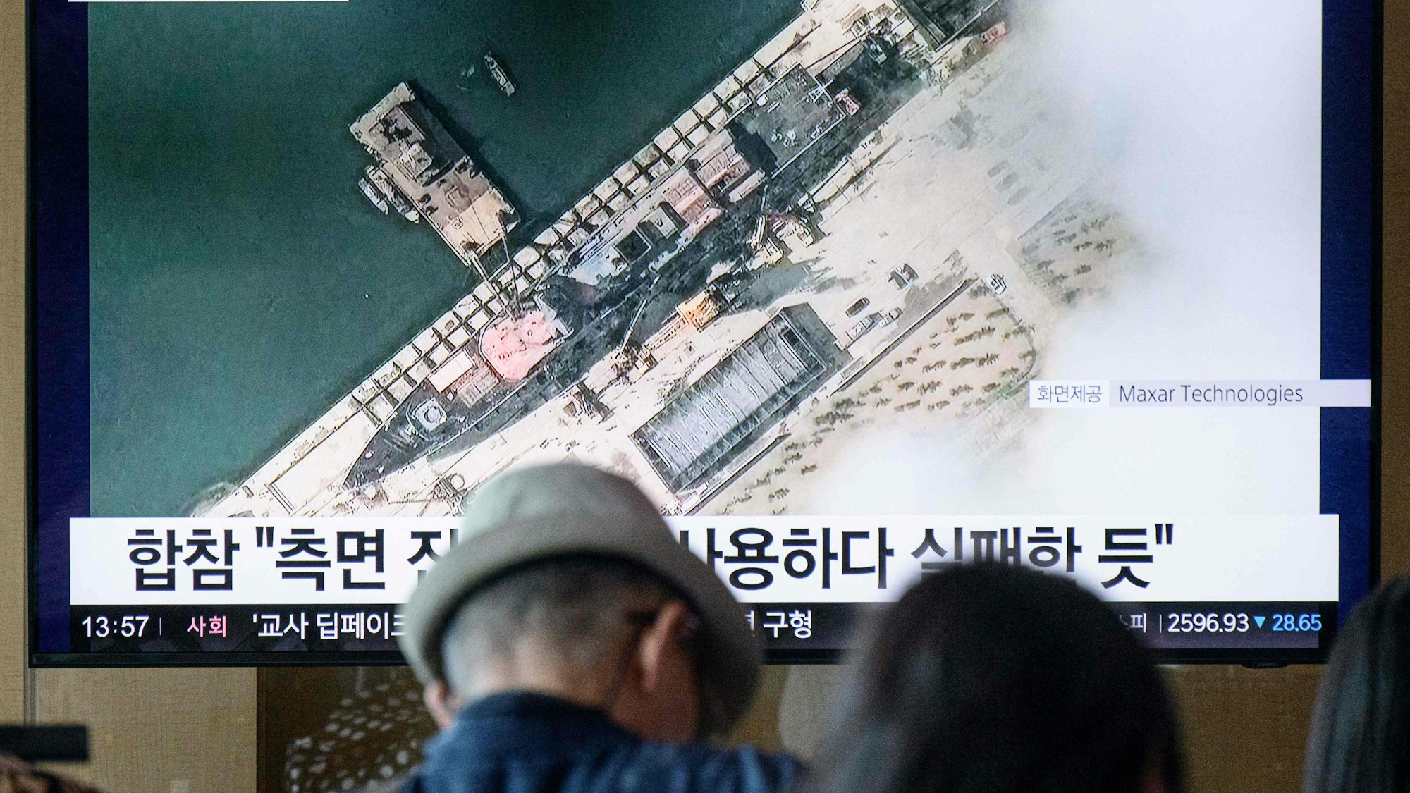 Menschen betrachten ein Satellitenbild, das von Maxar Technologies am 18. Mai 2025 aufgenommen und am 22. Mai 2025 zur Verfügung gestellt wurde und eine Gesamtansicht eines neuen nordkoreanischen Kriegsschiffs im Hafen von Chongjin zeigt. (Archivbild)