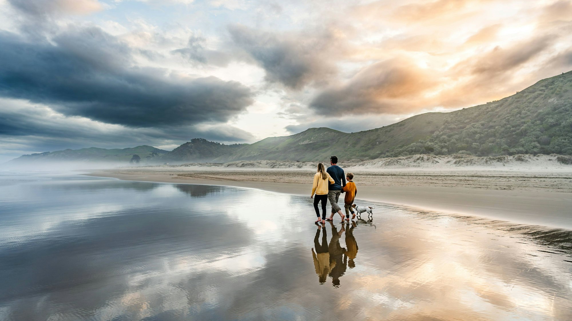 Familie mit Hund beim Spaziergang am Strand.