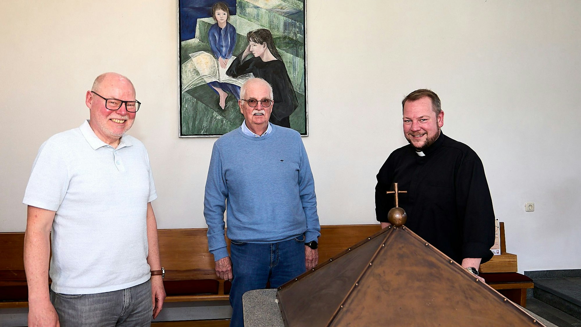 Drei Männer stehen in der Kirche St. Anna in Hellenthal. Sie lachen.