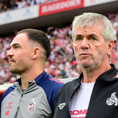 Friedhelm Funkel steht vor einem FC-Spiel vor der Trainerbank.