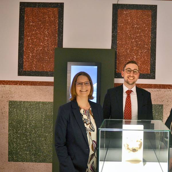Dr. Silva Bruder, Dustin Hoferichter und Lisa Kröger stehen hinter einer Vitrine.