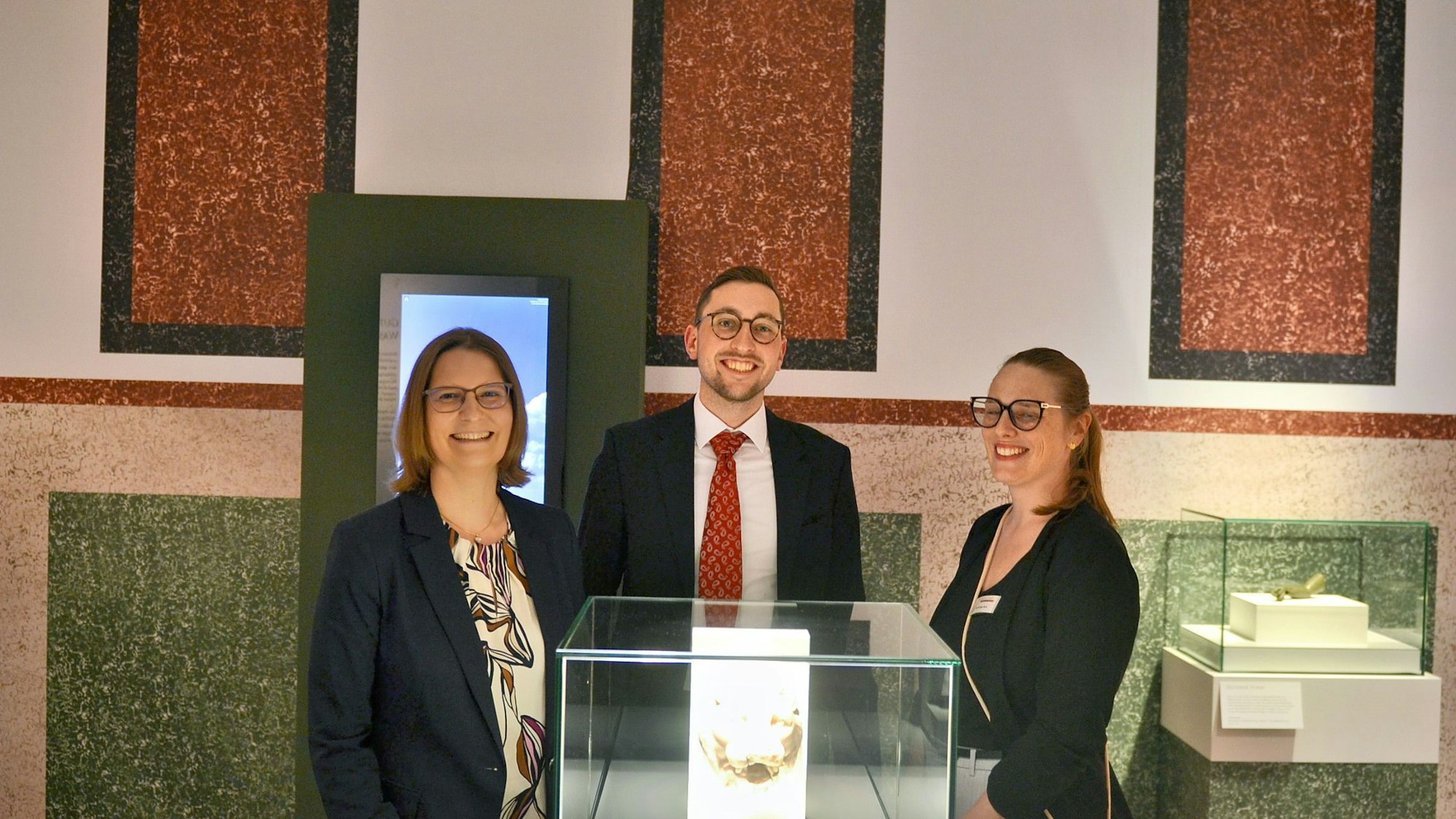 Dr. Silva Bruder, Dustin Hoferichter und Lisa Kröger stehen hinter einer Vitrine.