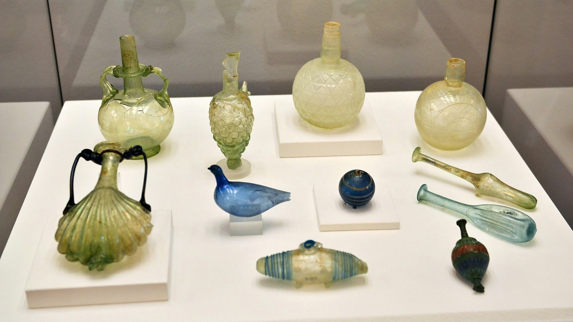 Mehrere Gefäße stehen oder liegen in einer Vitrine.