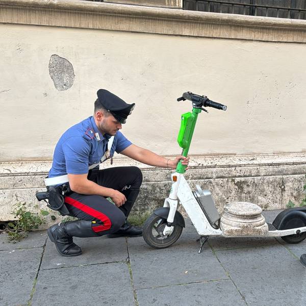 Zwei Carabiniere stehen neben dem E-Scooter mit der antiken Marmorsockelplatte.