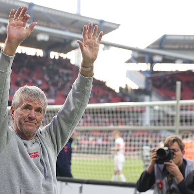 Ein Fußballtrainer reckt seine Arme in die Höhe.