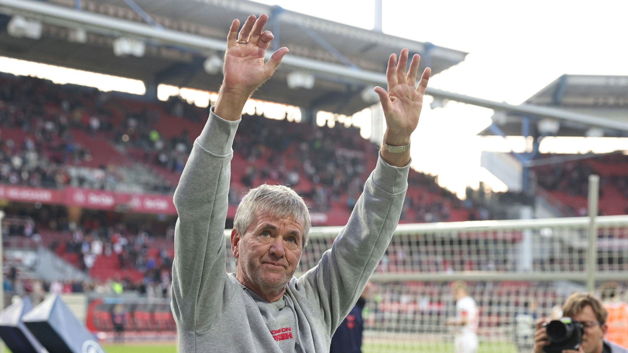 Ein Fußballtrainer reckt seine Arme in die Höhe.