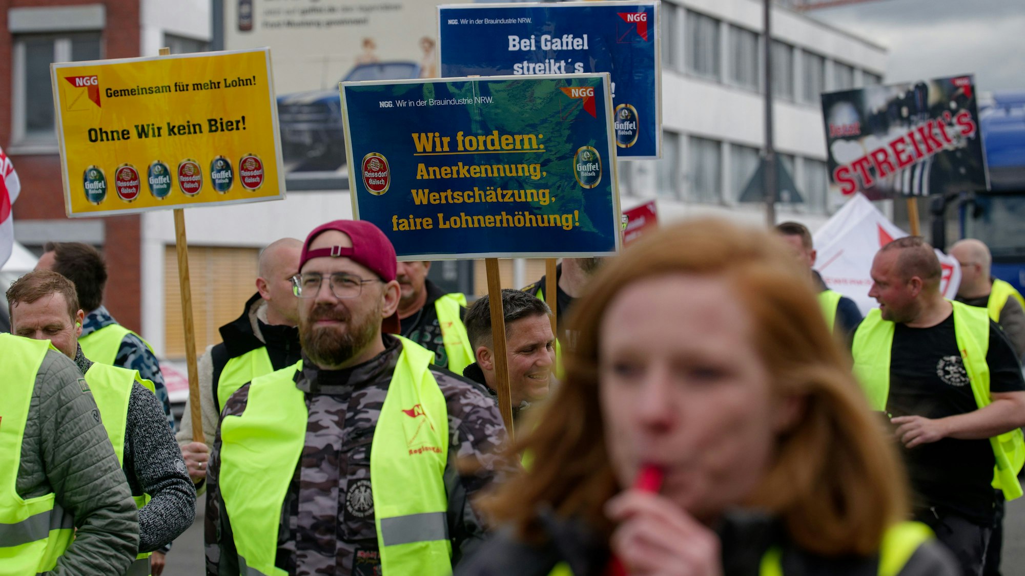 Mitarbeiter der beiden Kölsch-Brauereien Gaffel und Reissdorf halten bei einem Warnstreik vor der Gaffelbrauerei in Köln-Porz Schilder. Zu dem Ausstand hat die Gewerkschaft Nahrung-Genuss-Gaststätten (NGG) aufgerufen.