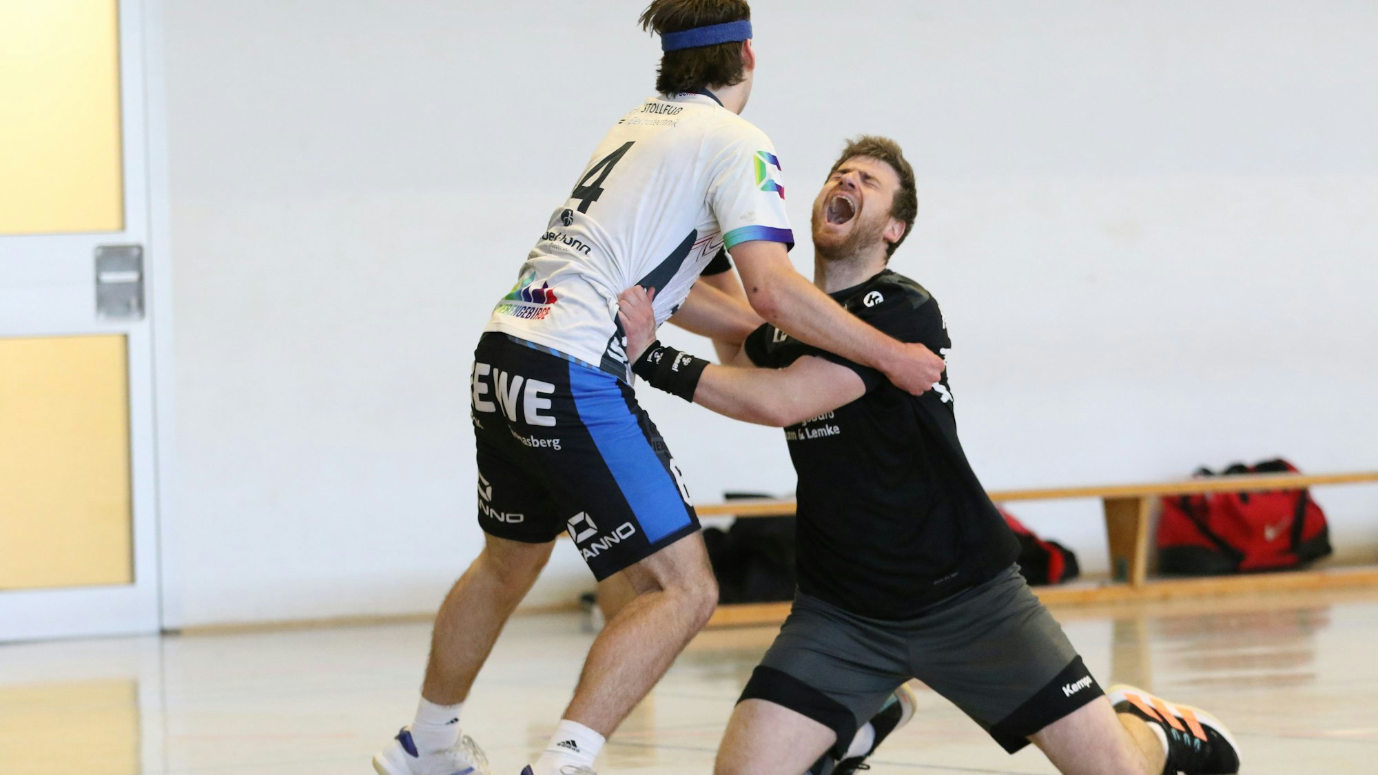 Kalls Nils Kühl schreit seinen Schmerz hinaus und hockt, den Gegenspieler noch im Arm, auf den Knien.