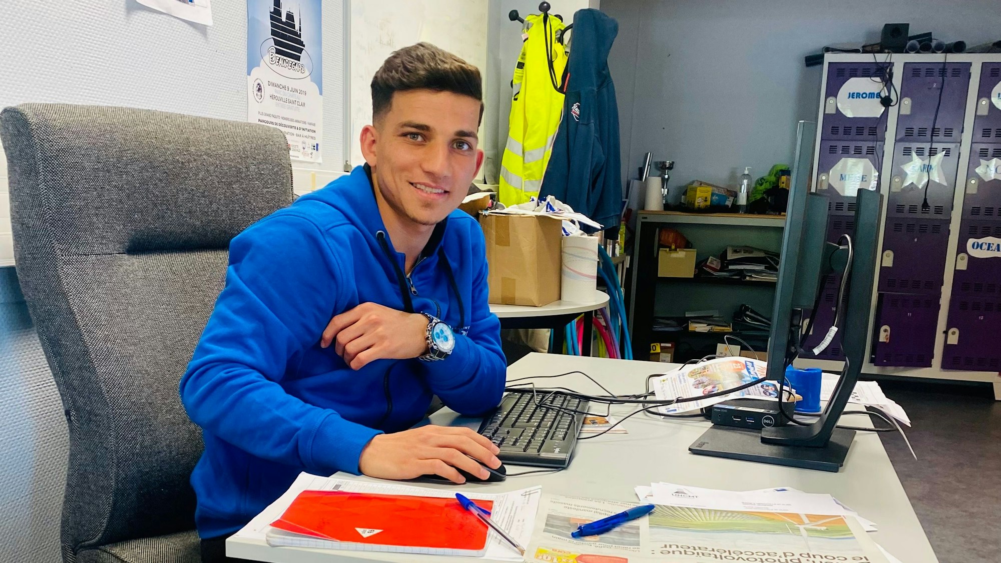 Sufjan Ato Shawrdi am Schreibtisch seines Arbeitgebers, er lächelt in die Kamera.