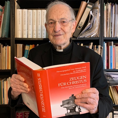 Das Foto zeigt Prälat Helmut Moll mit dem von ihm herausgegeben Werk über katholische Märtyrer.