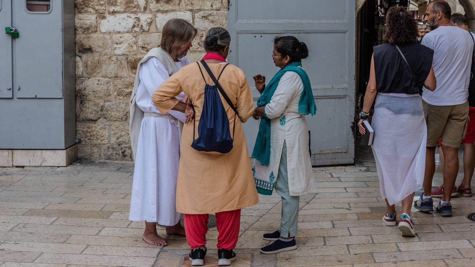 Ein Jesus-Darsteller spricht in Jerusalem vor der Grabeskirche mit zwei Pilgerinnen.