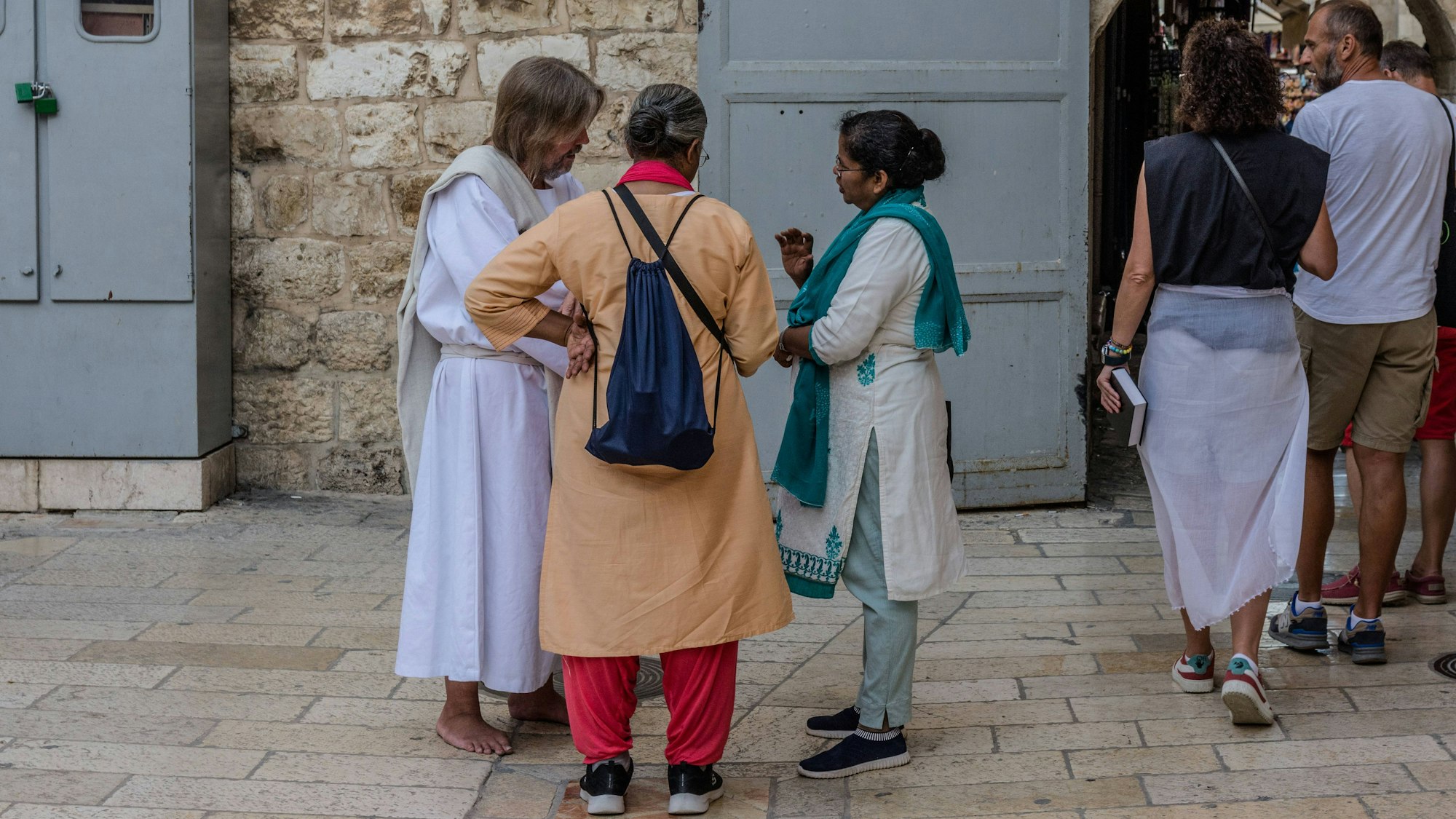 Ein Jesus-Darsteller spricht in Jerusalem vor der Grabeskirche mit zwei Pilgerinnen.