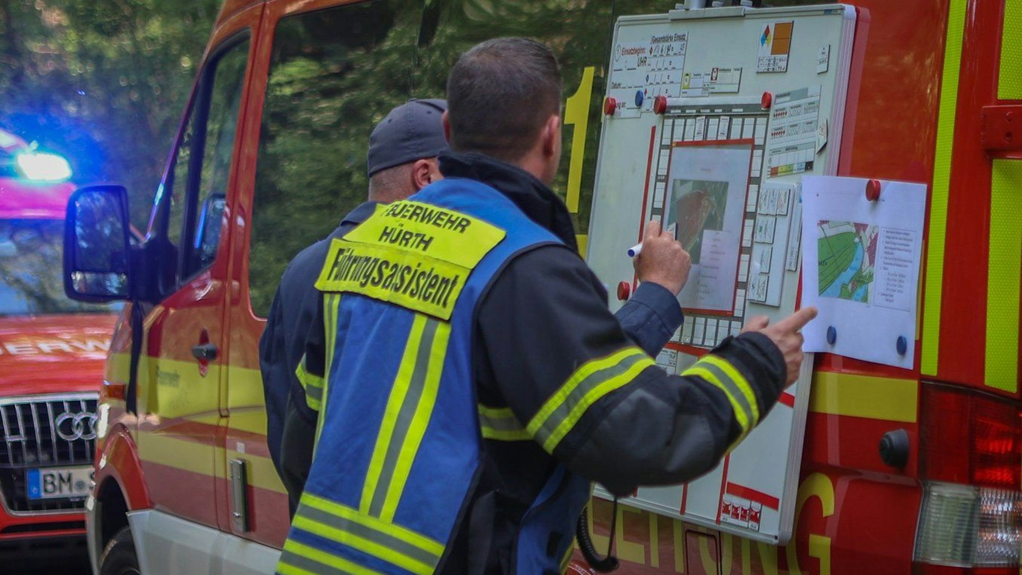 Lagebesprechung: Feuerwehrleute sondieren das Einsatzgebiet und die Zuwegungen in den Wald.