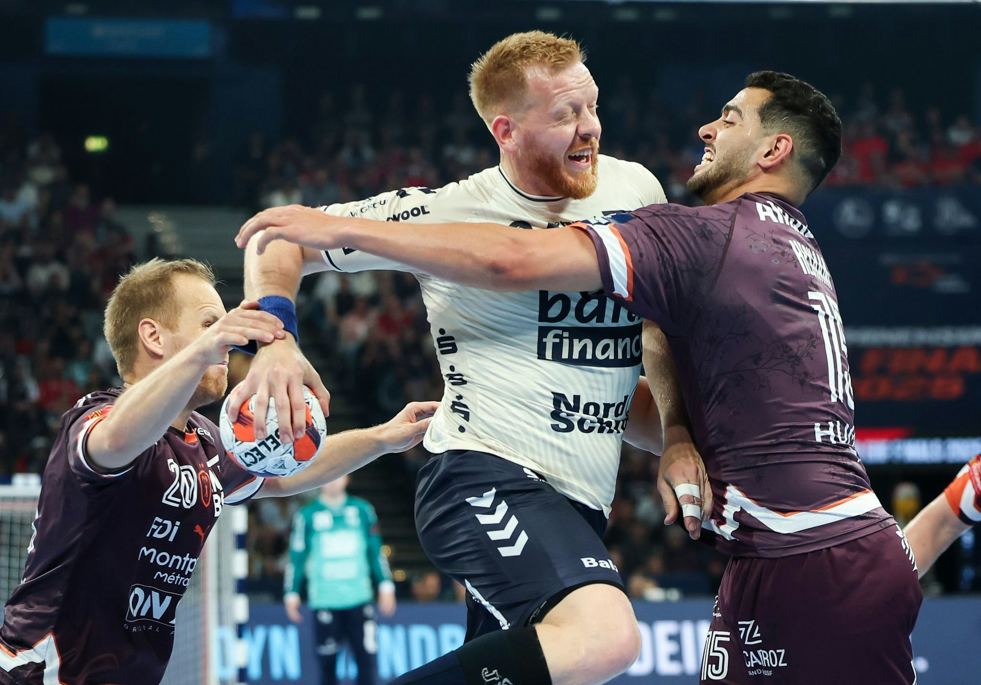 Flensburgs Jim Gottfridsson (M) wird von Montpelliers Stas Skube (l) und Ahmed Hesham am Wurf gehindert.