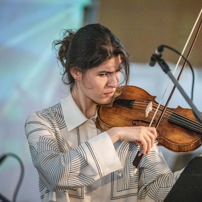 Musikerin Ekaterina Perlina steht in einem weißen Oberteil mit ihrer Violine bei einem Konzert der Kammermusik aus dem 18. Jahrhundert im Veranstaltungsaal Ventana.