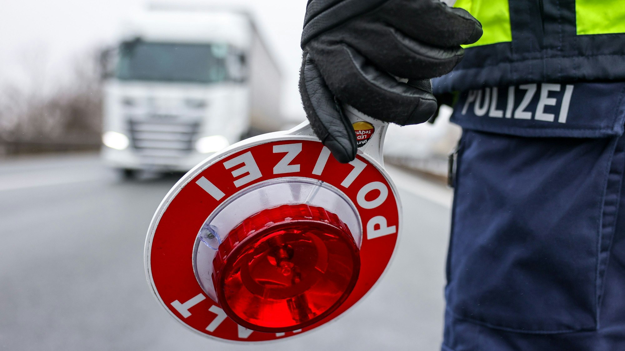 Ein Polizist hält eine Polizeikelle für eine Kontrolle an der Autobahn 72.