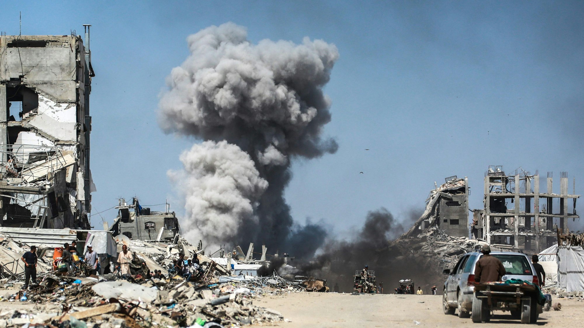 People watch as smoke billows following an Israeli strike in Jabalia, in the northern Gaza Strip on May 25, 2025. Rescuers in Gaza said 22 people were killed and dozens more wounded in Israeli air strikes across the Palestinian territory on May 25. (Photo by Bashar TALEB / AFP)