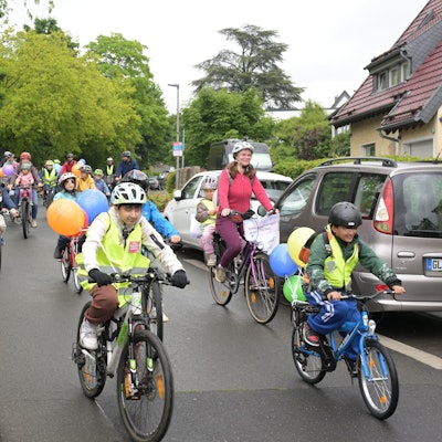 Kinder und Erwachsene fahren mit Fahrrädern im Protestzug über eine Straße.
