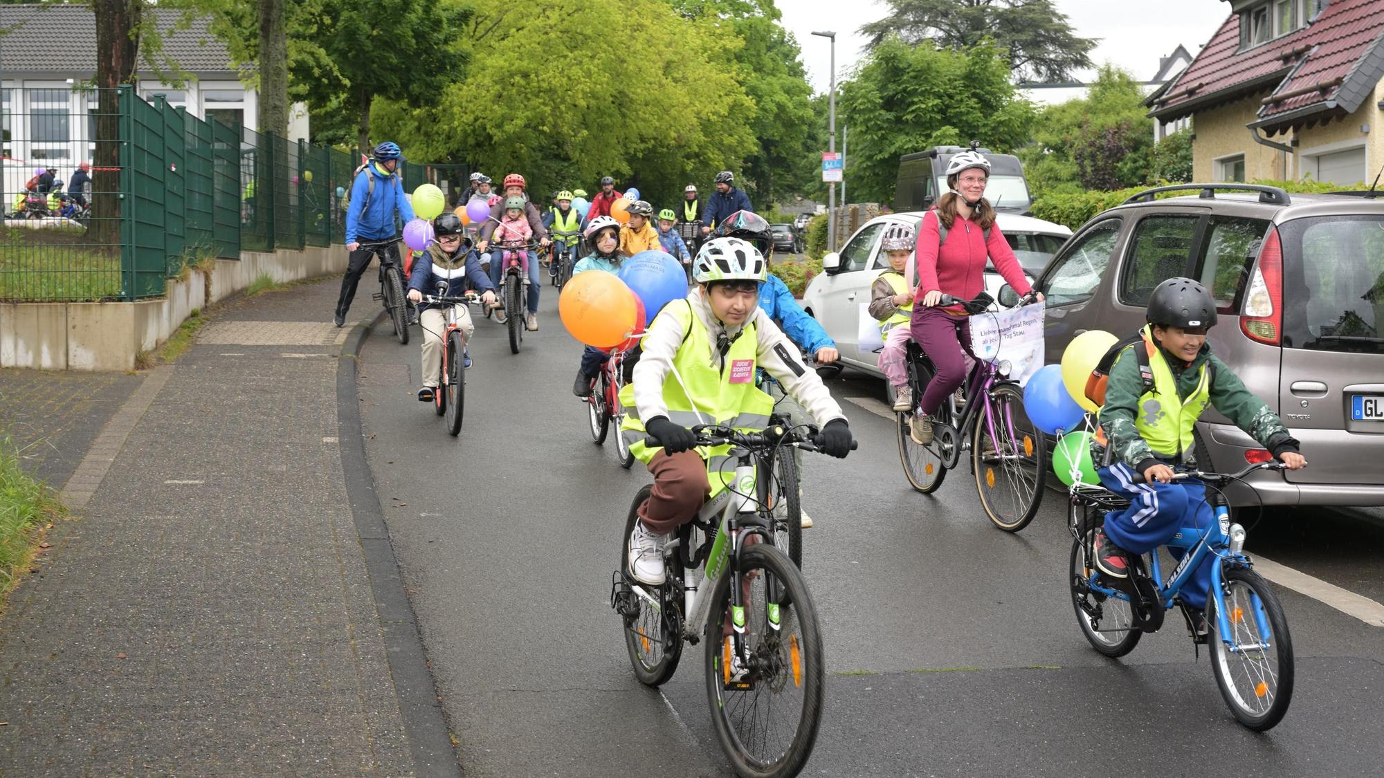Kinder und Erwachsene fahren mit Fahrrädern im Protestzug über eine Straße.