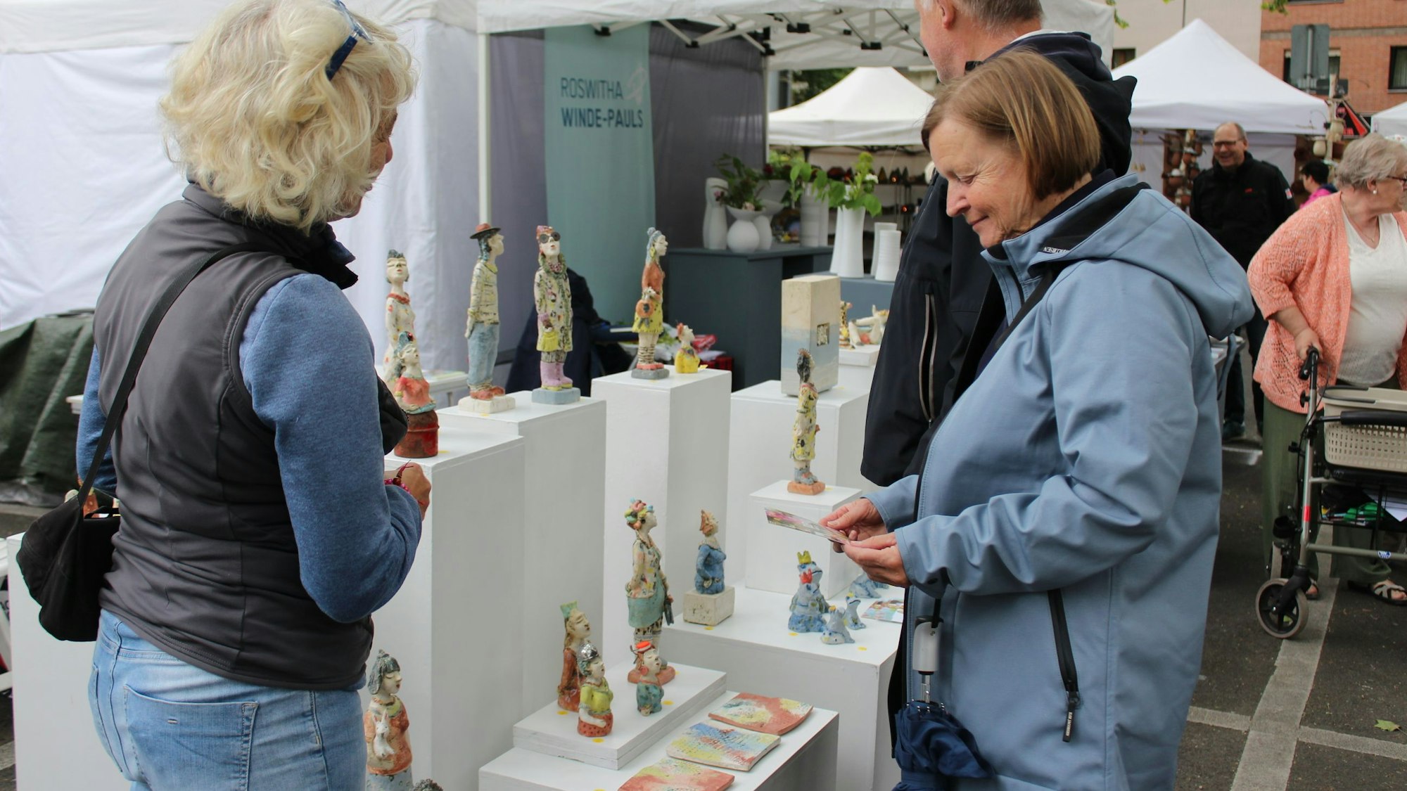Zu sehen ist ein Stand auf dem Töpfermarkt, an dem es kleine Figuren zu kaufen gibt.