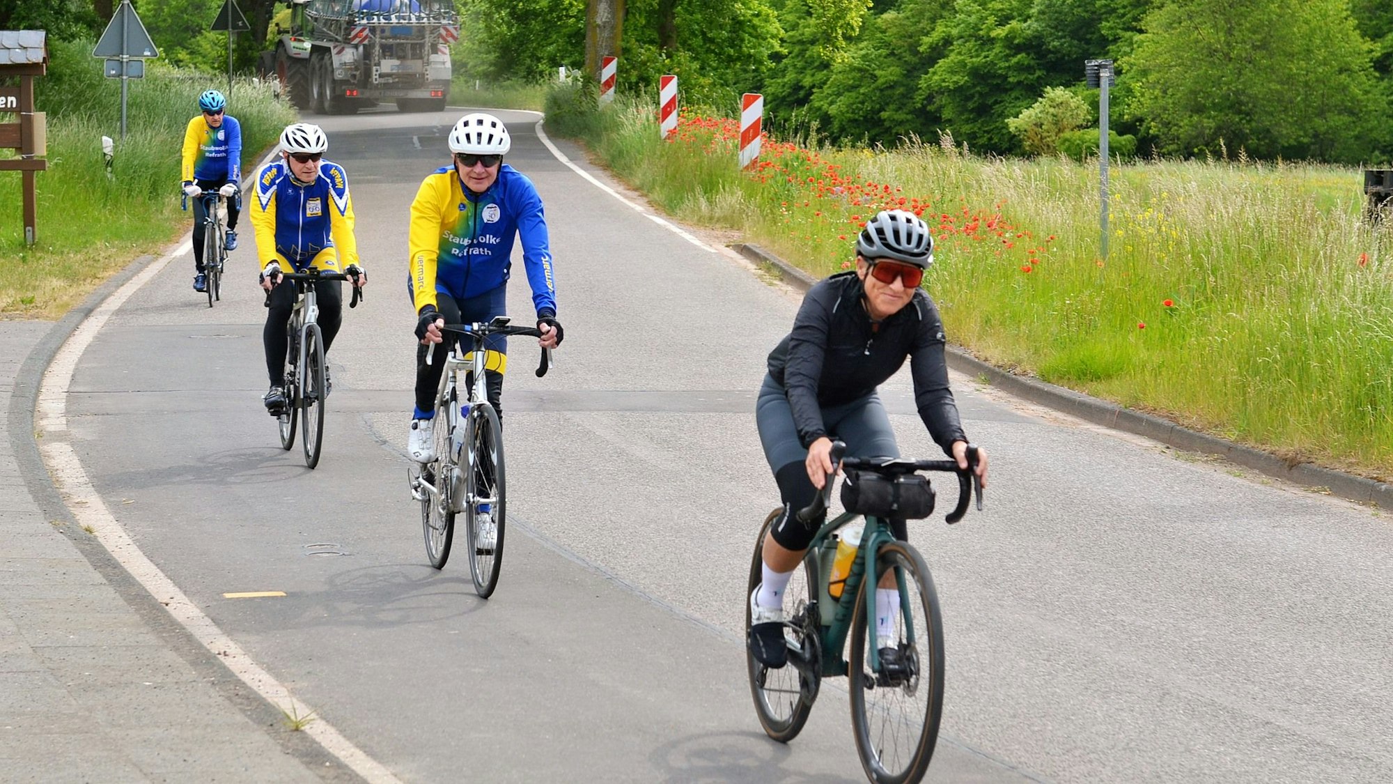 Auf einer Landstraße fahren vier Radfahrer hintereinander.