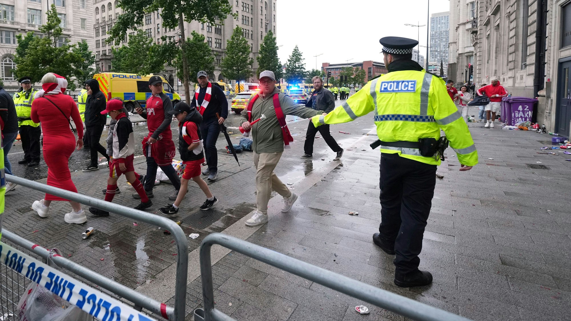 26.05.2025, Großbritannien, Liverpool: Fans verlassen das Stadion, während Polizei und Rettungskräfte in der Water Street in der Nähe des Liver Building in Liverpool im Einsatz sind, nachdem ein Auto während der Premier-League-Siegerparade in eine Menschenmenge gefahren ist. (zu dpa Auto fährt in Menge: 53-Jähriger in Liverpool festgenommen) Foto: Jon Super/AP/dpa +++ dpa-Bildfunk +++