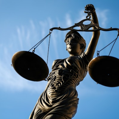 Die Bronzefigur einer Justitia hält zwei Waagschalen in der Hand.