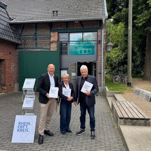 Eine Frau und zwei Männer halten jeweils ein Buch.